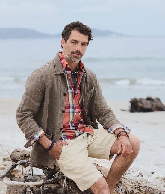 Modelo de Saville Row con campera y camisa a cuadros en la playa